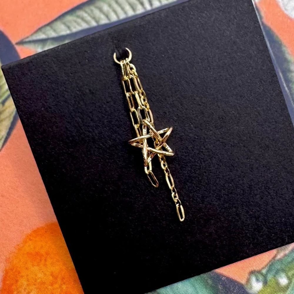 Front view of “Starfire” chain charm in yellow gold on black backing and clementine background with 16 gauge jump ring